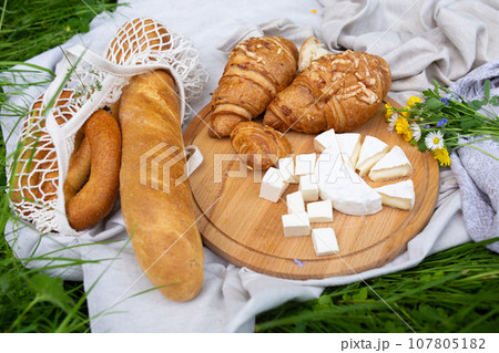 Picnic in the field with berries, juice, cheese, sausage and sweet croissants Picnic in the field with berries, juice, cheese, sausage and sweet croissants 107805182