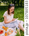 Beautiful woman on picnic. She smiles, eats strawberries and enjoys summer. 107805183