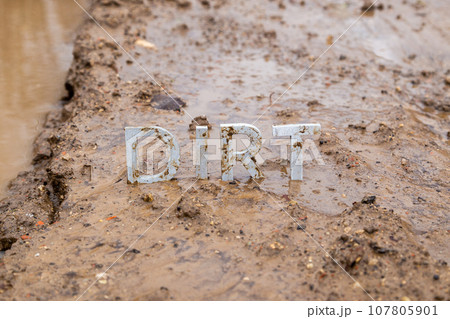 the word dirt composed of silver metal letters on wet clay surface the word dirt composed of silver metal letters on wet clay surface 107805901