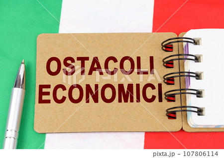 On the flag of Italy lies a pen and a notebook with the inscription - economic obstacles On the flag of Italy lies a pen and a notebook with the inscription - economic obstacles 107806114