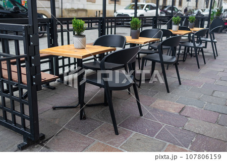 Modern street cafe with wooden tables with chairs standing next to them. Architecture and landmarks of Krakow.  107806159
