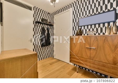 a bedroom with black and white patterned wallpaper on the walls, wooden furniture in the closet is next to the bed 107806822