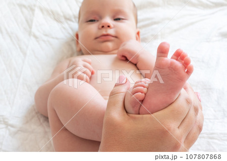 Mother's playtime with baby's tiny feet. Concept of cherished maternal moments Mother's playtime with baby's tiny feet. Concept of cherished maternal moments 107807868