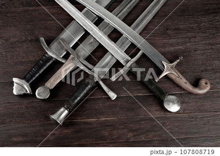 Swords and sabre on wooden background. 107808719