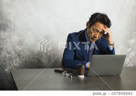 パソコンの前で考え込む男性 107809892