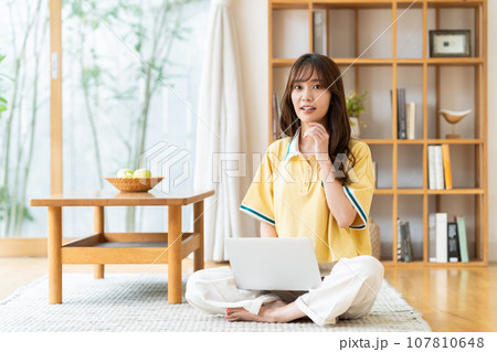 リビングでパソコンを見る若い女性 リビングでパソコンを見る若い女性 107810648
