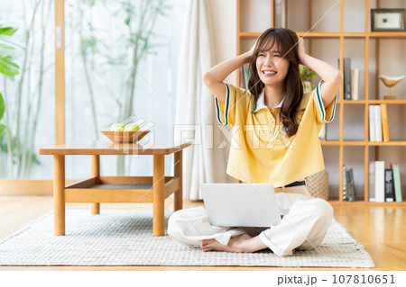 リビングでパソコンを見る若い女性 リビングでパソコンを見る若い女性 107810651