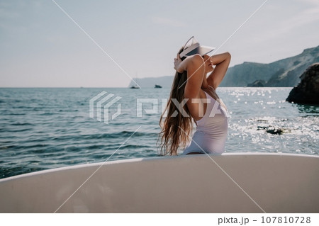 Woman sea sup. Close up portrait of happy young caucasian woman with long hair looking at camera and smiling. Cute woman portrait in a white bikini posing on sup board in the sea Woman sea sup. Close up portrait of happy young caucasian woman with long hair looking at camera and smiling. Cute woman portrait in a white bikini posing on sup board in the sea 107810728