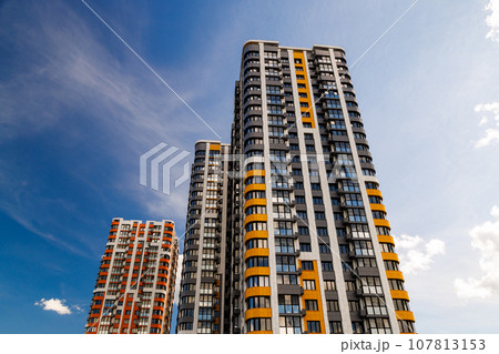 freshly built high rise apartment buildings on blue sky background with white clouds 107813153
