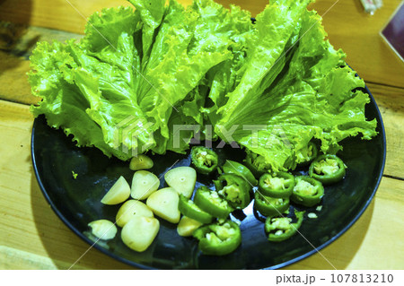 A plate of fresh lettuce, green peppers, and garlic, ready to be enjoyed in a delicious and nutritious meal. A plate of fresh lettuce, green peppers, and garlic, ready to be enjoyed in a delicious and nutritious meal. 107813210