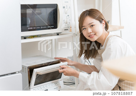 オーブンレンジを使う若い女性 107818807