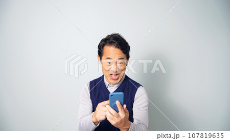 スマホを見て興奮するミドル男性 107819635