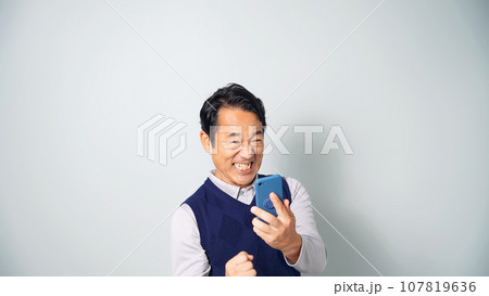 スマホを見て興奮するミドル男性 107819636