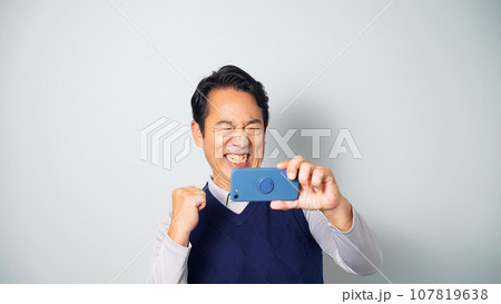 スマホを見て興奮するミドル男性 107819638