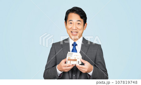 住宅模型を見せる中年ビジネスマン 107819748