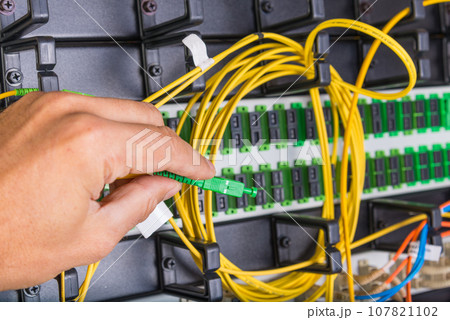closeup of hand of administrator connecting network cable into switch 107821102
