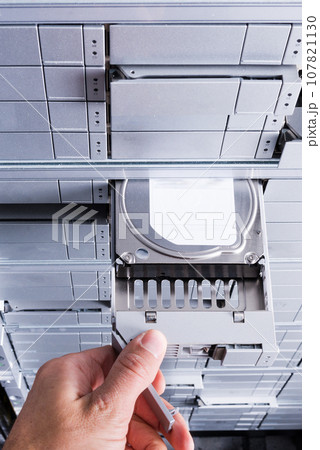 hand of IT technician installing hard drive with SAS interface into data storage server 107821130