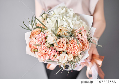 Small Beautiful bouquets of mixed flowers in woman hand. Floral shop concept . Beautiful fresh cut bouquet. Flowers delivery 107821533