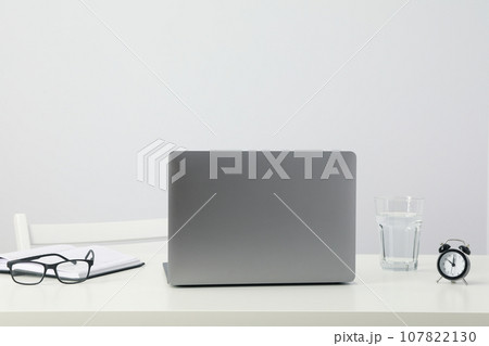 Laptop, glasses, glass and alarm clock on table on white background 107822130