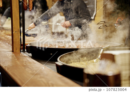 Process of cooking street food outdoors. Frying pan with fried dishes. Christmas Fair at Wroclaw main square Process of cooking street food outdoors. Frying pan with fried dishes. Christmas Fair at Wroclaw main square 107823004