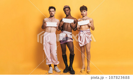 Trans people covering their breasts with white sign on yellow background Trans people covering their breasts with white sign on yellow background 107823688