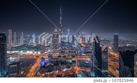 Panorama showing aerial view of tallest towers in Dubai Downtown skyline and highway night timelapse. 107825946