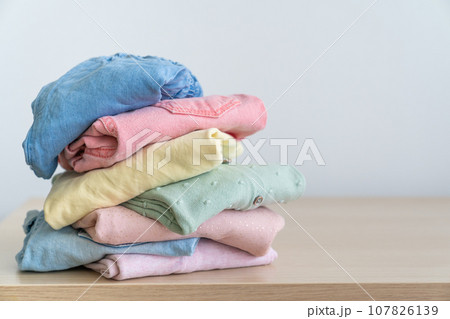 Stack of clean freshly laundered, neatly folded women's clothes on wooden table 107826139