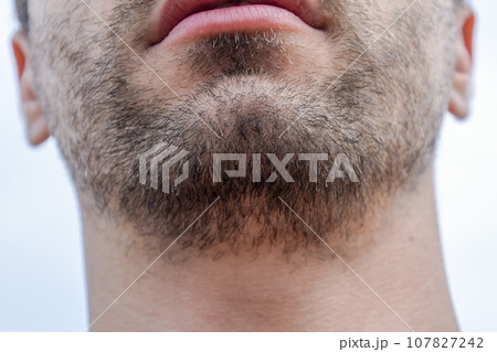 Bearded male chin. Beard on the face of a young man. 107827242
