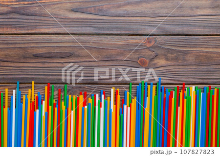 Heap of colorful plastic drinking straws on Colored background, flat lay. Copy Space for text Heap of colorful plastic drinking straws on Colored background, flat lay. Copy Space for text 107827823