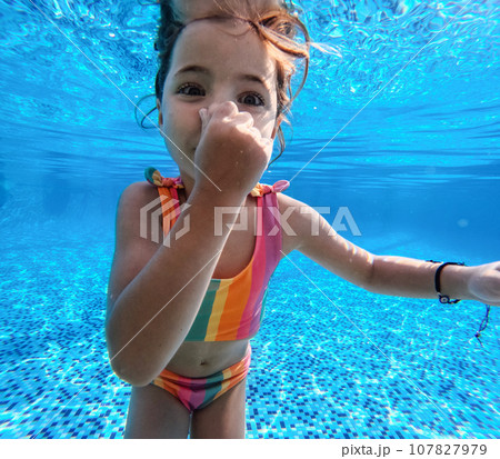 Girl diving underwater in the pool during summer vacation, playing in the water. Winter or summer seaside holiday. Underwater photography. 107827979