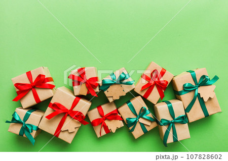 wrapped christmas or other holiday handmade present in paper with colored ribbon. Present box, decoration of gift on colourfull table, top view with copy space 107828602