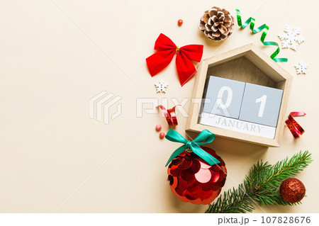 Christmas calendar 1 january. Christmas gift, fir branches, pine cones. Flat lay, top view. New Year decorations on a colored background 107828676