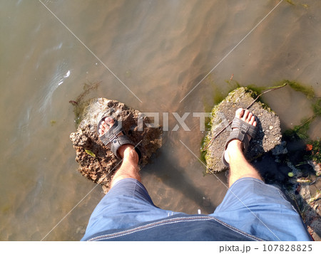 man stands on rocks with his feet on the bank of the river. Feet on rocks. river. 107828825