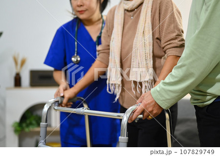 Practitioner nurse assisting senior female walking with walker. Healthcare service and rehabilitation 107829749