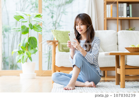 リビングでスマホ見る若い女性 107830239