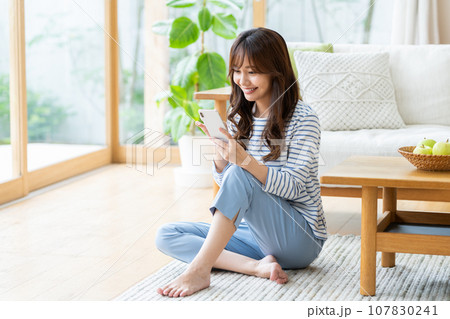 リビングでスマホ見る若い女性 107830241