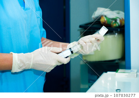 The doctor fills a syringe with medicine from an ampoule. The doctor fills a syringe with medicine from an ampoule. 107830277