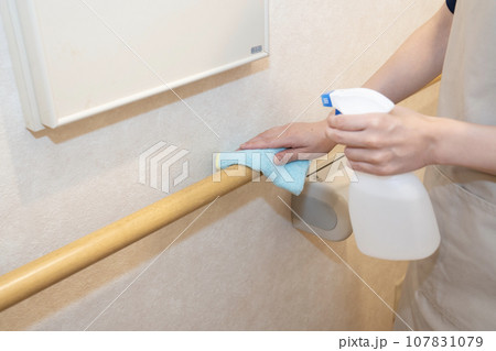 トイレの手すりにアルコールをスプレーする女性 107831079