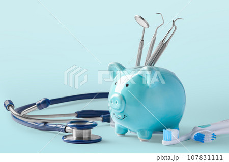 Dental cost concept, piggy bank with dentist instruments on blue background, copy space 107831111
