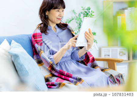 リビングでタブレットを見る中年女性 107831403