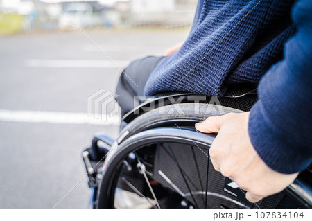 車椅子を漕ぐ男性 107834104