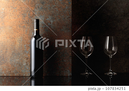 Bottle of red wine with empty wine glasses on rusty brown background. Bottle of red wine with empty wine glasses on rusty brown background. 107834251