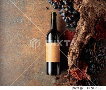 Bottle of red wine with blue grapes on a rusty background. Bottle of red wine with blue grapes on a rusty background. 107834328