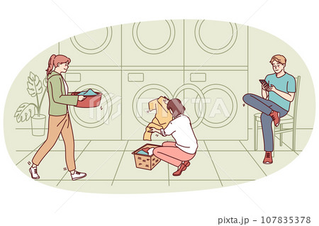 People washing clothes in laundromat 107835378