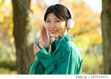 秋晴れの公園で音楽を楽しむ女性 秋晴れの公園で音楽を楽しむ女性 107835451