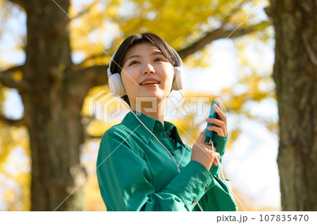 秋晴れの公園で音楽を楽しむ女性 秋晴れの公園で音楽を楽しむ女性 107835470