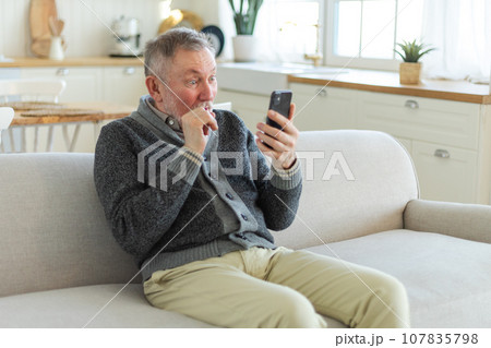 Happy middle aged senior man talk on video call with friends family. Laughing mature old senior grandfather having fun speaking with grown up children online. Older generation modern tech usage 107835798