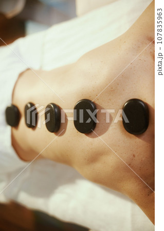 Woman having hot stone massage and laying on massage table 107835963