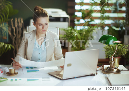 pensive woman employee in light business suit in green office 107836145