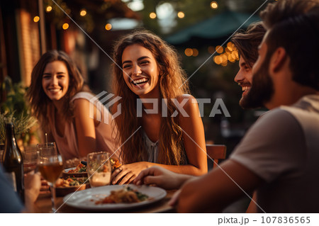 A Group of Friends Share Laughter and Delight as They Enjoy a Scrumptious Dinner at an Outdoor Restaurant. created with Generative AI 107836565
